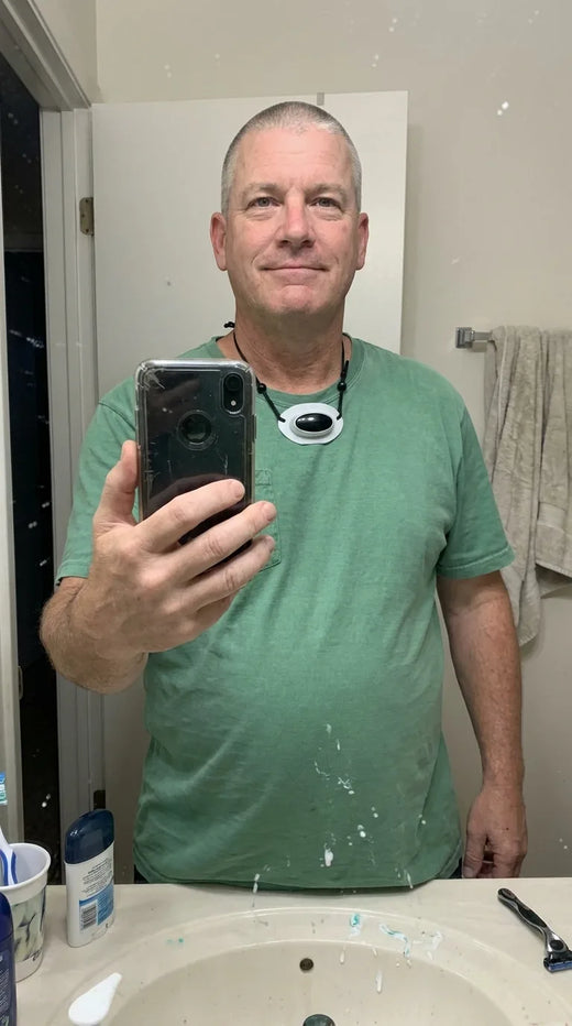 Man taking a bathroom mirror selfie with Hushlea Pro hanging on its cords around his neck
