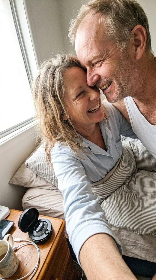 Couple laughing together in bed in the morning, the Hushlea Pro case open on the nightstand
